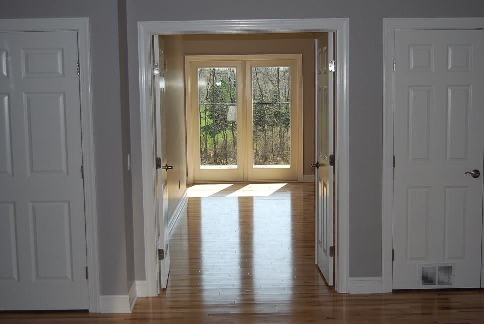 a hallway with white doors and a hard wood floor