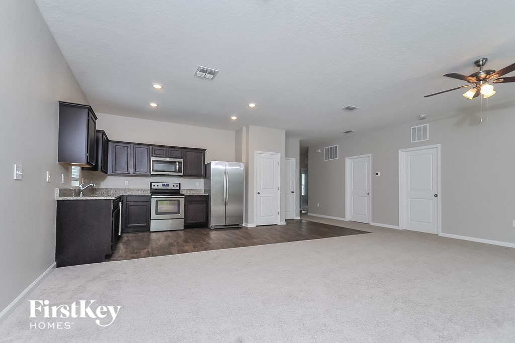 a spacious kitchen with stainless steel appliances and a ceiling fan