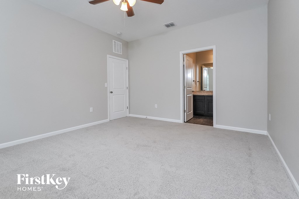 a spacious living room with white carpet and a ceiling fan