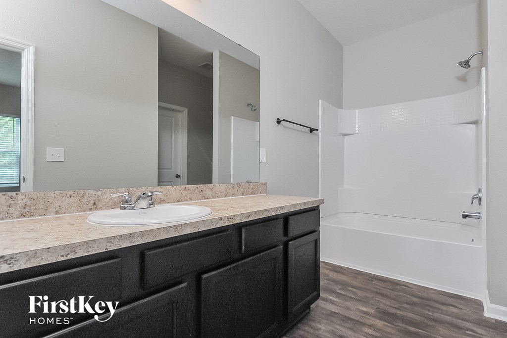 a bathroom with a sink and a shower and a mirror