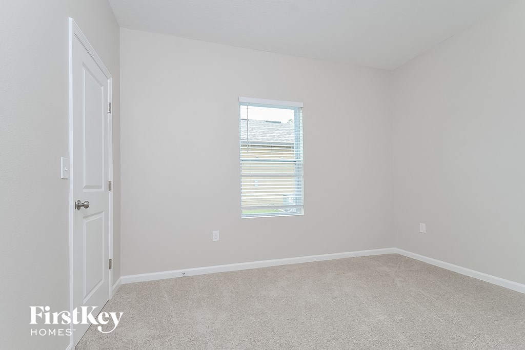 a bedroom with white carpet and a window