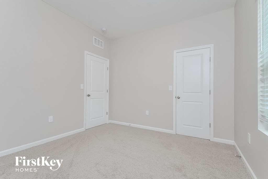 a bedroom with two doors and a carpeted floor