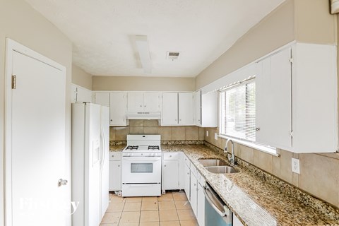 A kitchen with white appliances and cabinets.