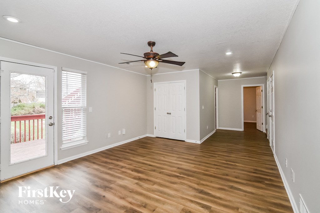 A spacious room with wooden floors and a ceiling fan.