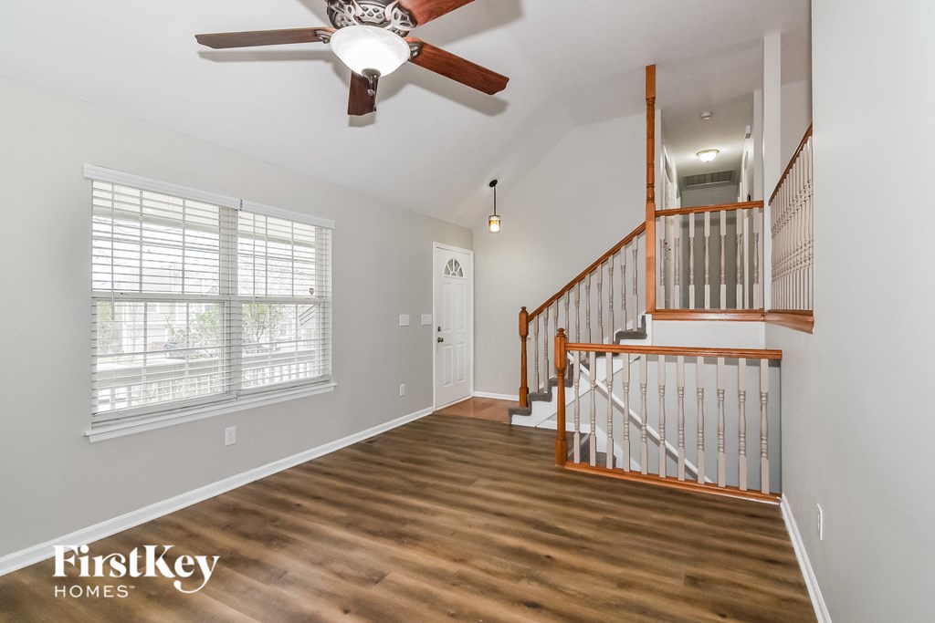 A spacious room with a wooden staircase and a ceiling fan.