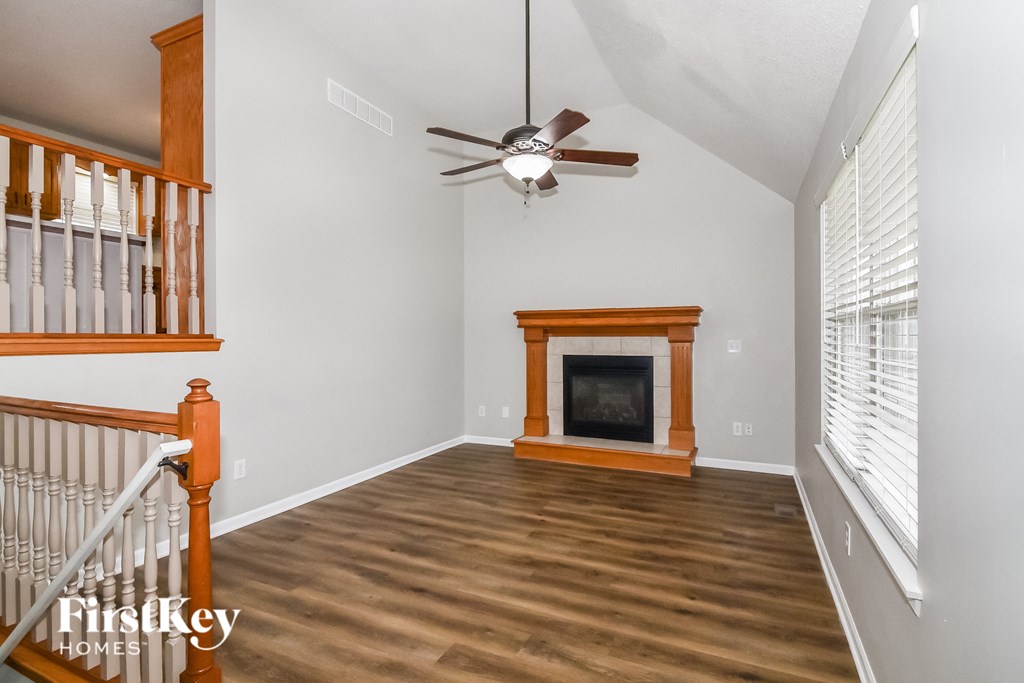 A living room with a fireplace and a ceiling fan.