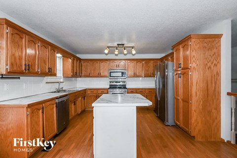 A kitchen with wooden cabinets and a white island.
