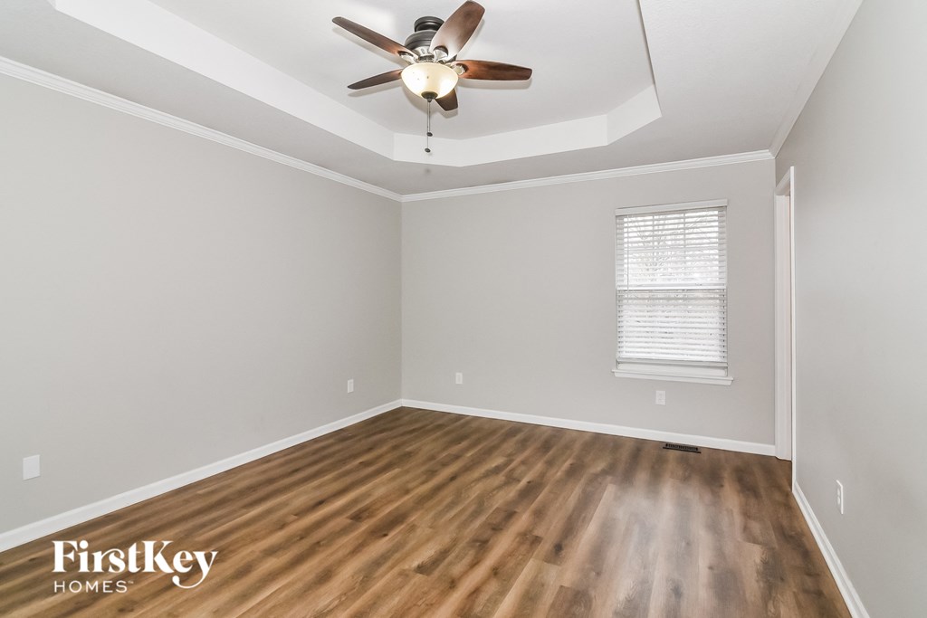A room with a ceiling fan and wooden flooring.