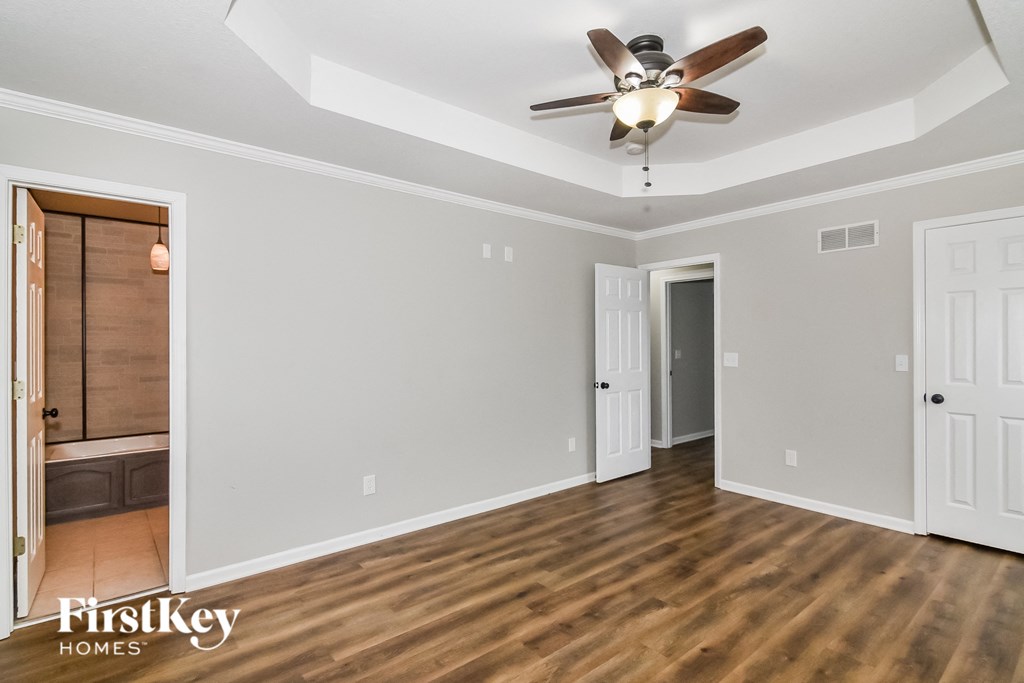 A room with a ceiling fan and wooden floors.