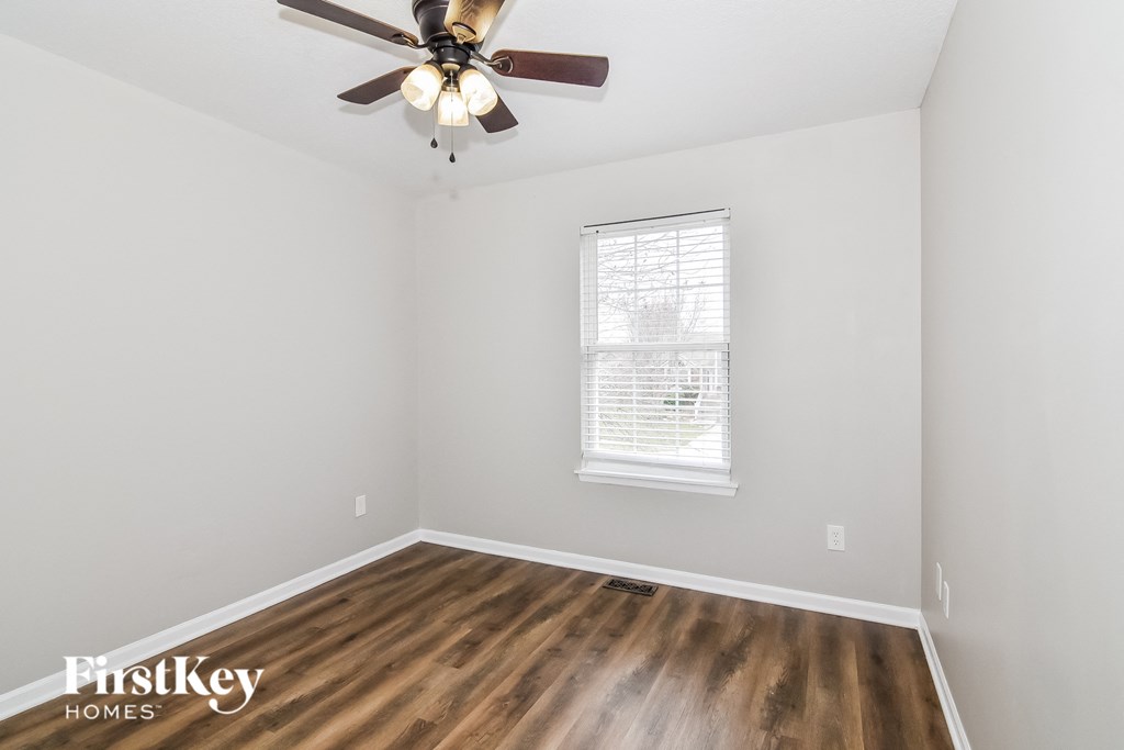 A room with a ceiling fan and wooden flooring.