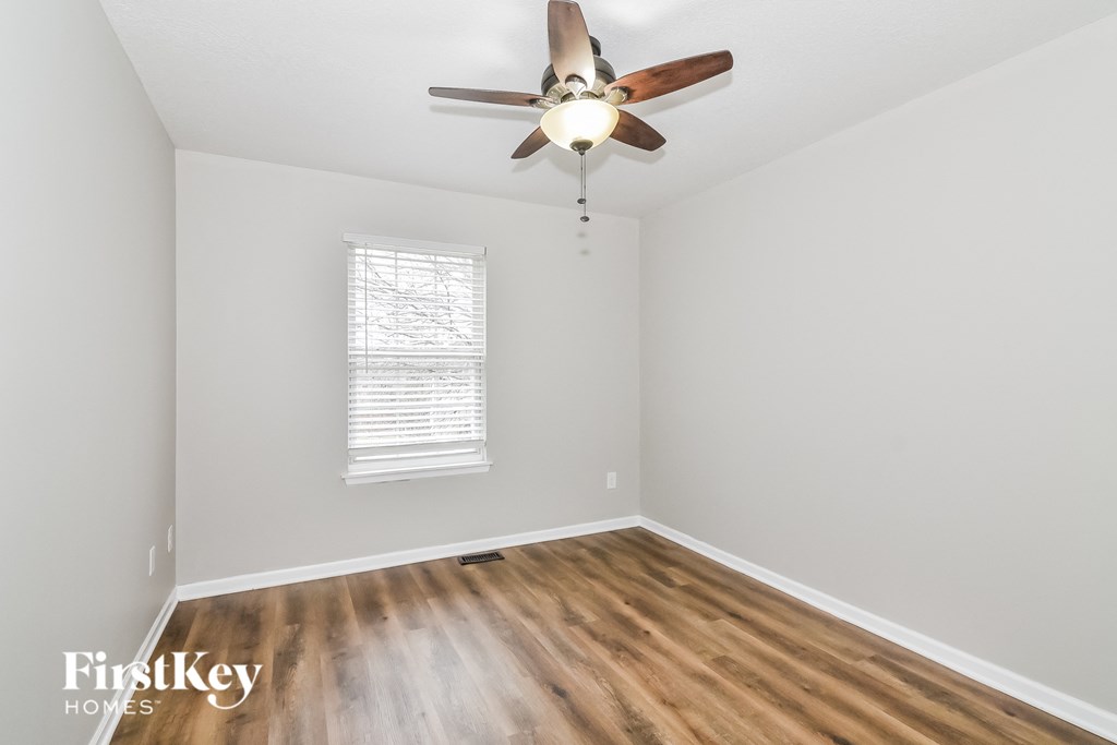 A room with a ceiling fan and wooden floors.