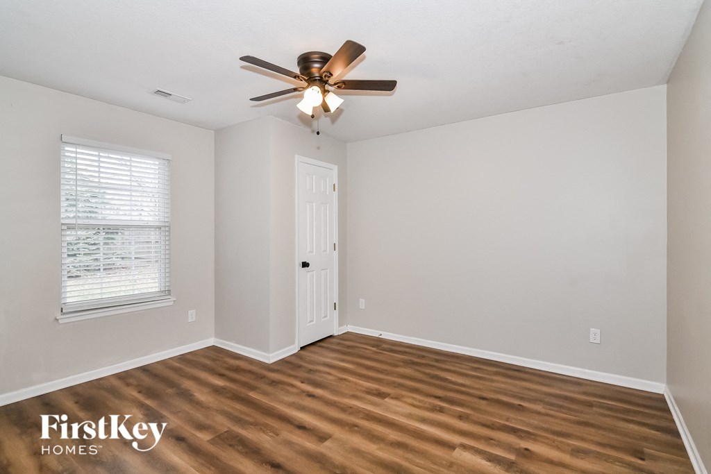 A room with a ceiling fan and wooden flooring.