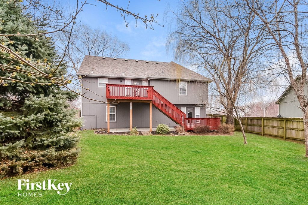A house with a red deck and a tree in front of it.