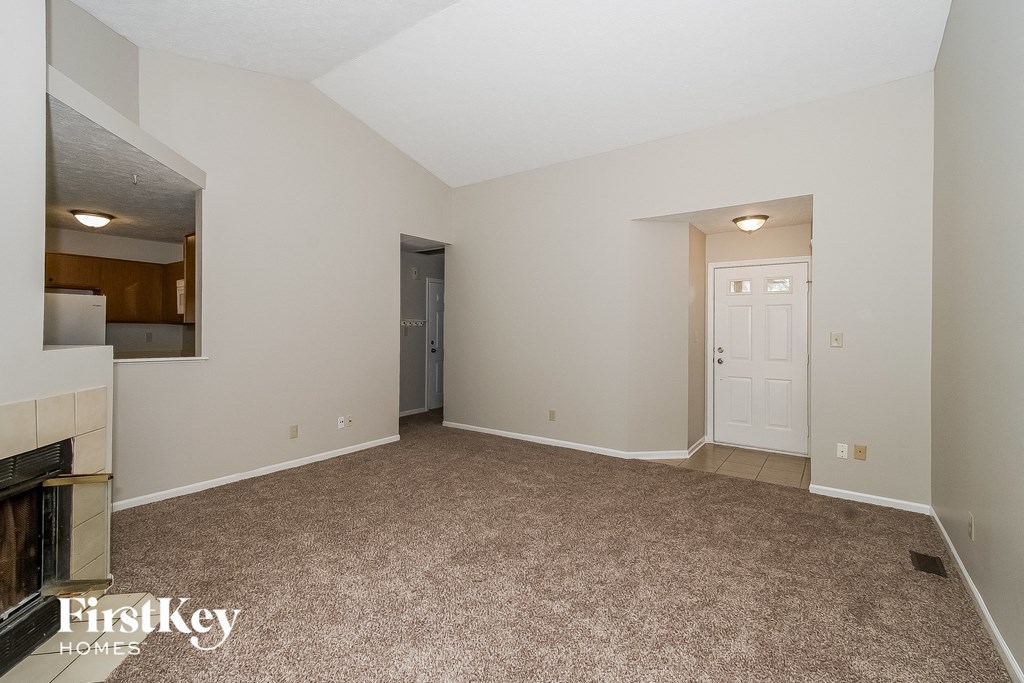 A spacious room with a fireplace and a door leading to another room.