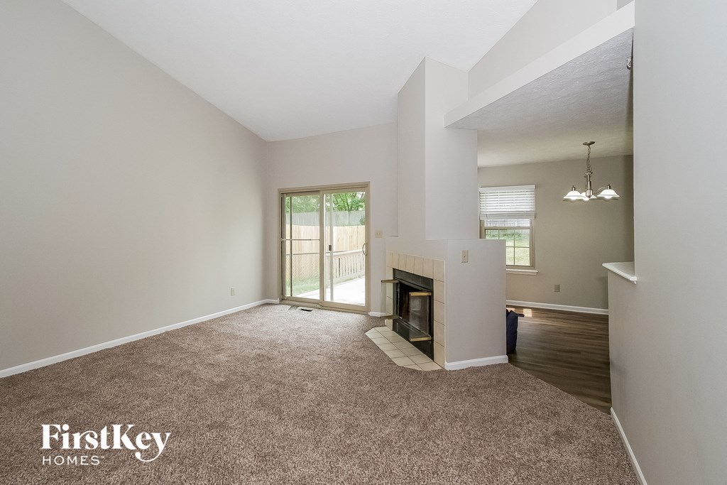 A spacious living room with a fireplace and sliding glass doors leading to a deck.