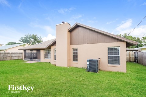 a beige house with a yard and a heater in the grass