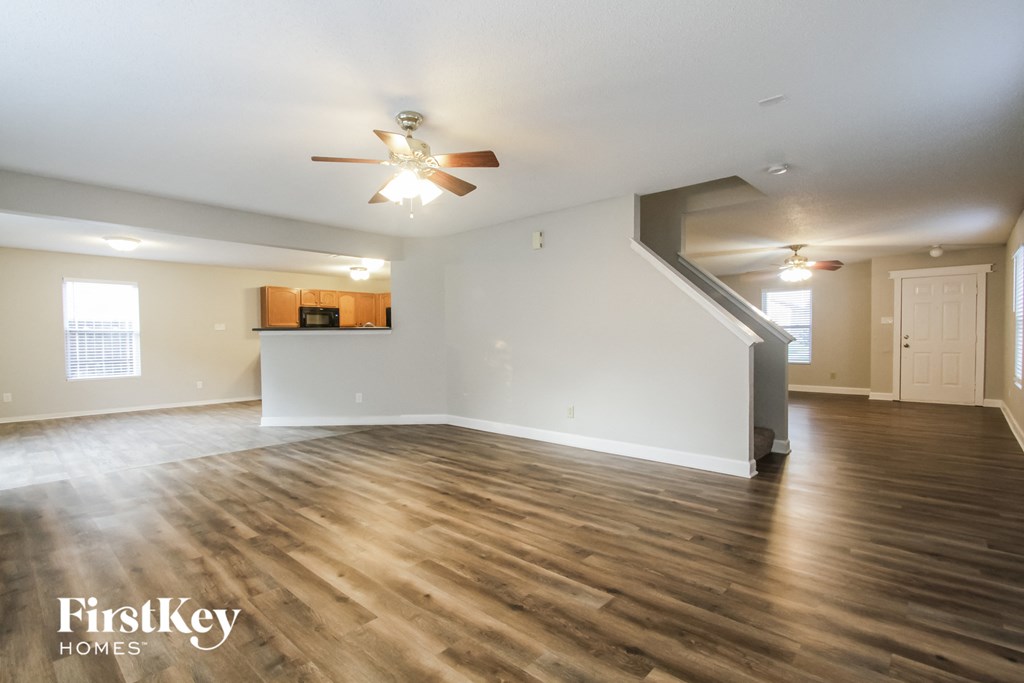 the living room of an empty house with a ceiling fan