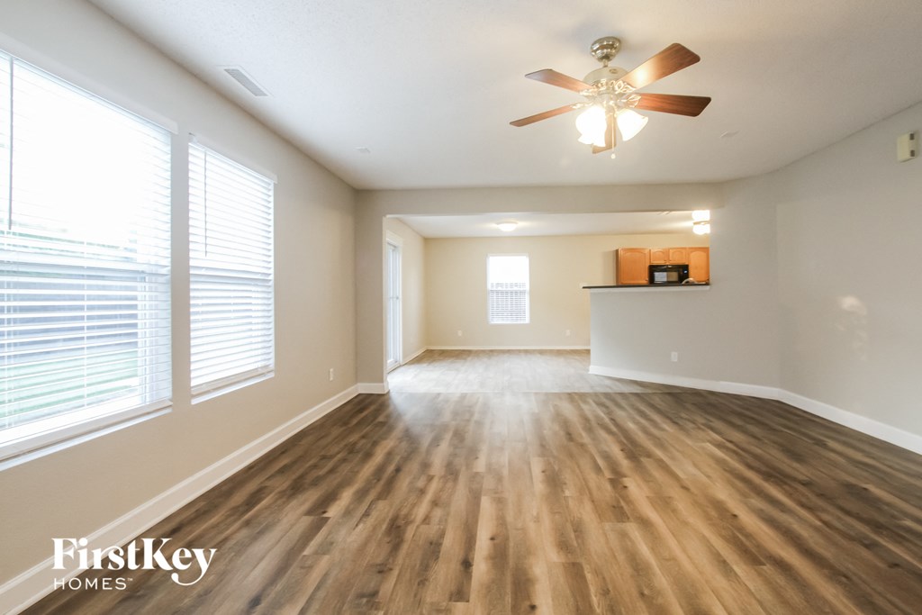 an empty living room with wood floors and a ceiling fan