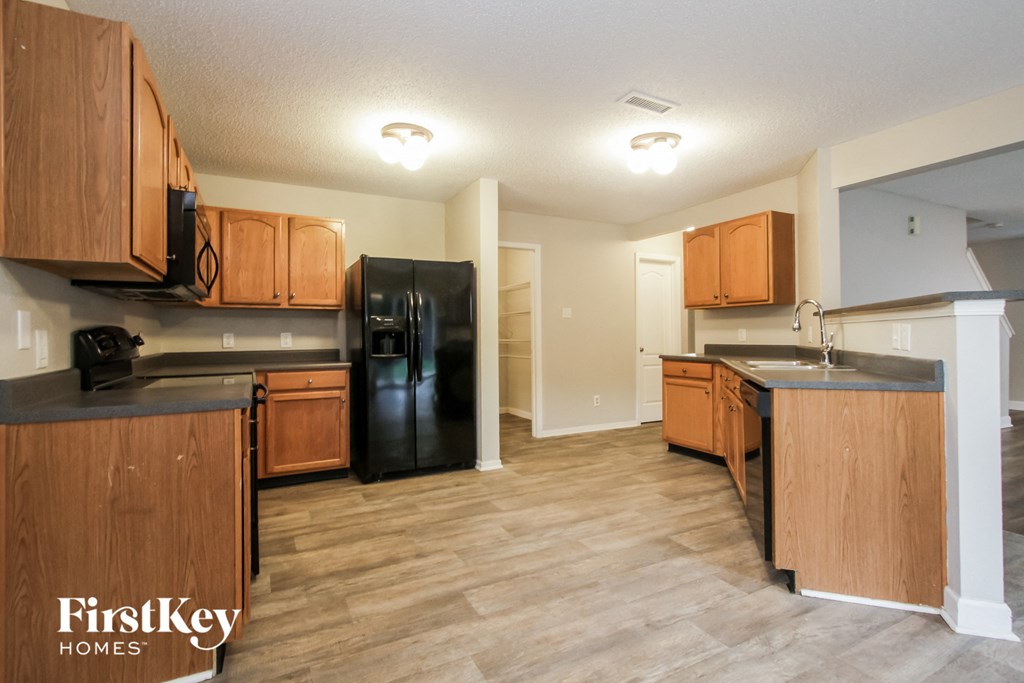a kitchen with wooden cabinets and a black refrigerator