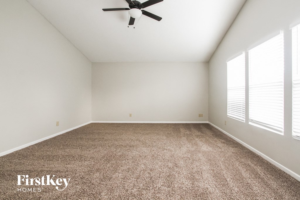 an empty room with a ceiling fan and a carpet
