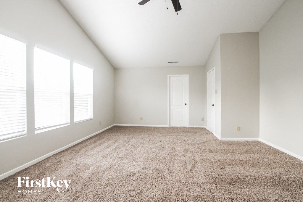 an empty room with a carpeted floor and three windows