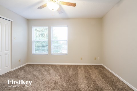 a spacious living room with carpet and a ceiling fan