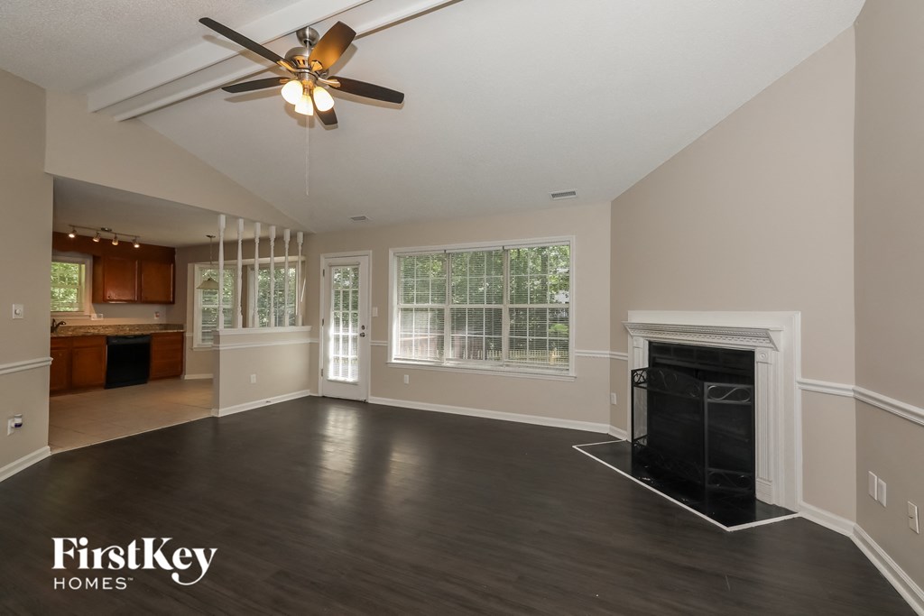 A spacious living room with a fireplace and a ceiling fan.