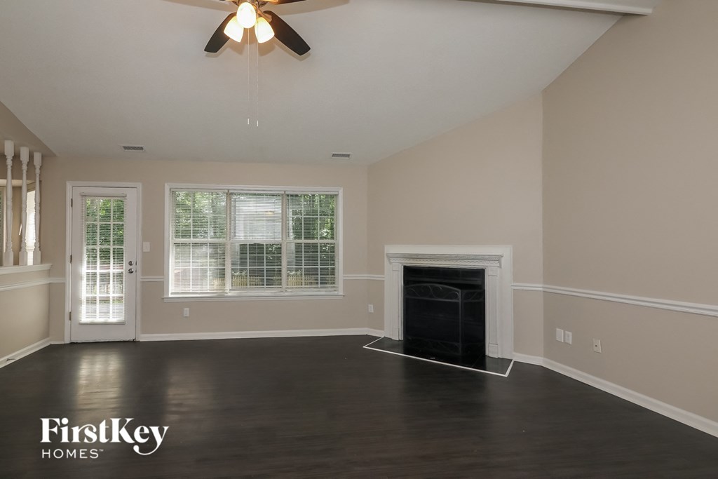 A spacious room with a fireplace and a ceiling fan.