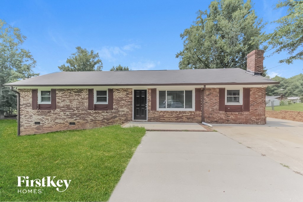 a small brick house with a driveway and grass