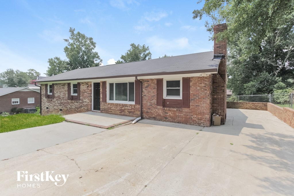 a small brick house with a driveway and a brick wall