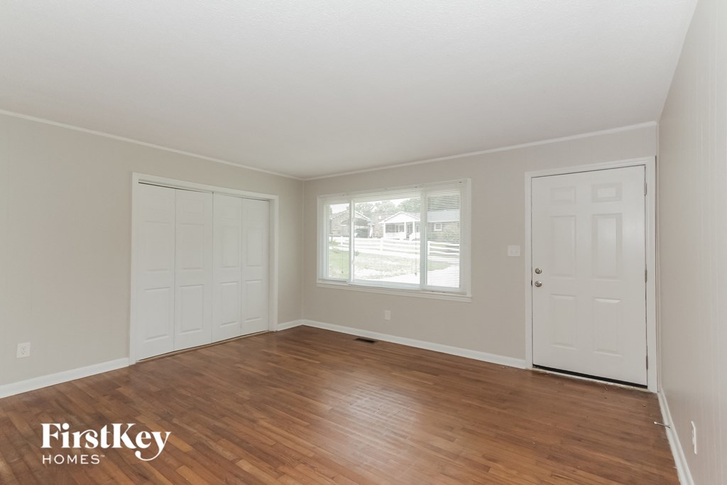 the living room of a home with a wooden floor and white doors