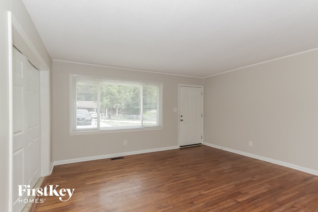 the living room of a home with a wooden floor and a large window