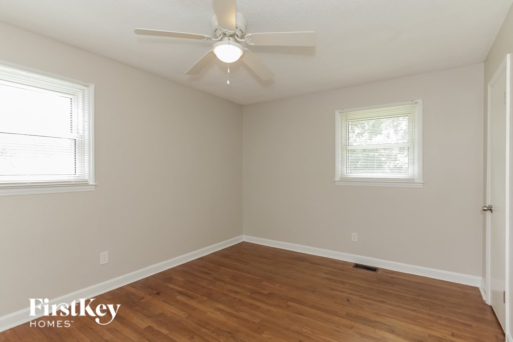an empty room with a ceiling fan and two windows