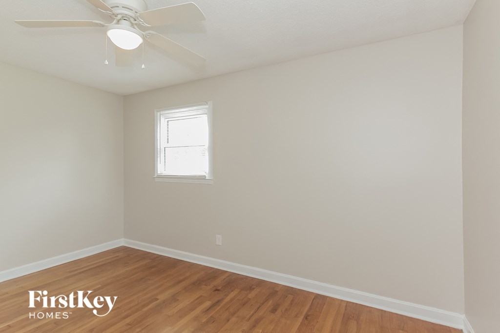 a bedroom with white walls and a ceiling fan