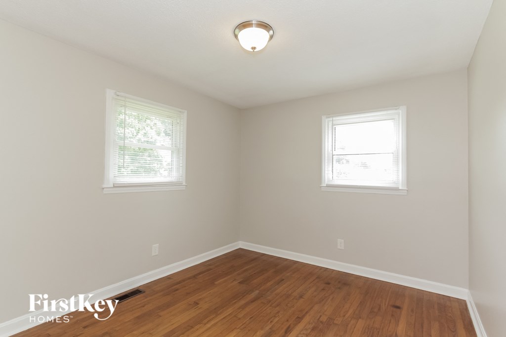 a bedroom with a hard wood floor and two windows