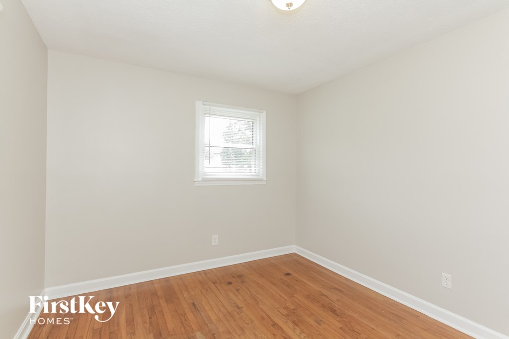a bedroom with a wooden floor and white walls and a window