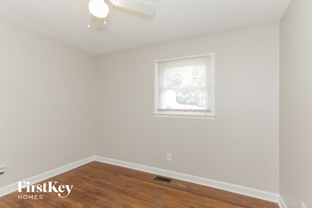 a bedroom with a hardwood floor and a window and a ceiling fan