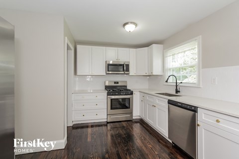 A kitchen with white cabinets and a wooden floor.