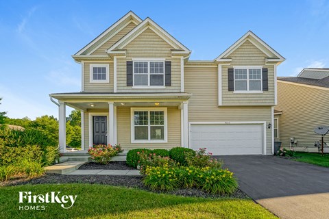 a yellow house with a driveway and a white garage door
