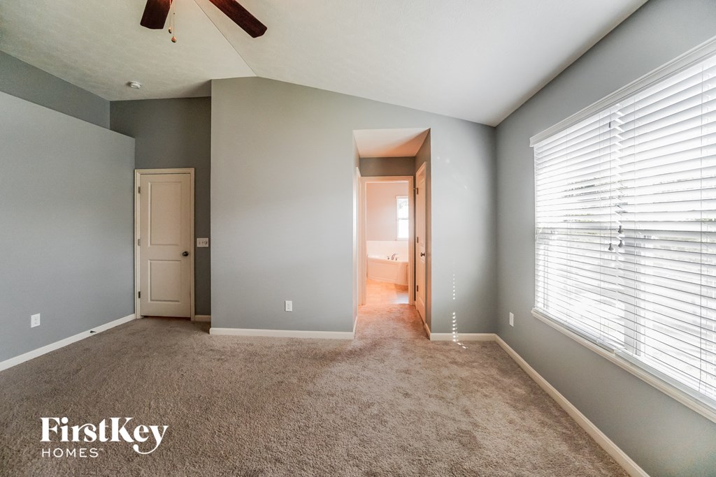 a carpeted living room with a large window and gray walls