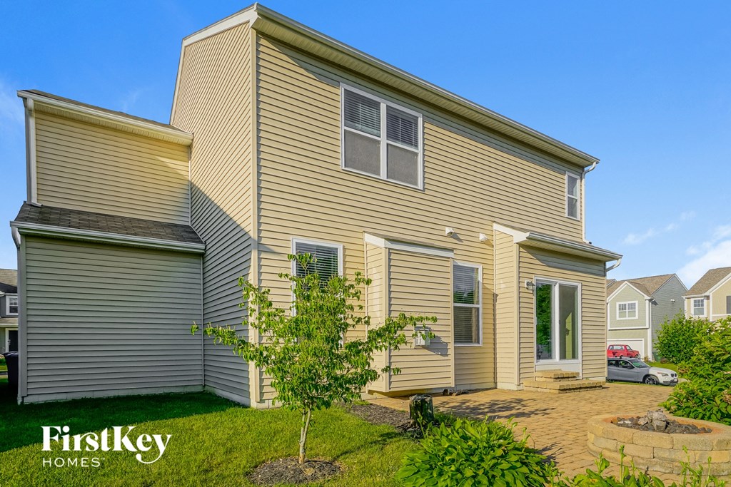 a yellow house with a small tree in the yard