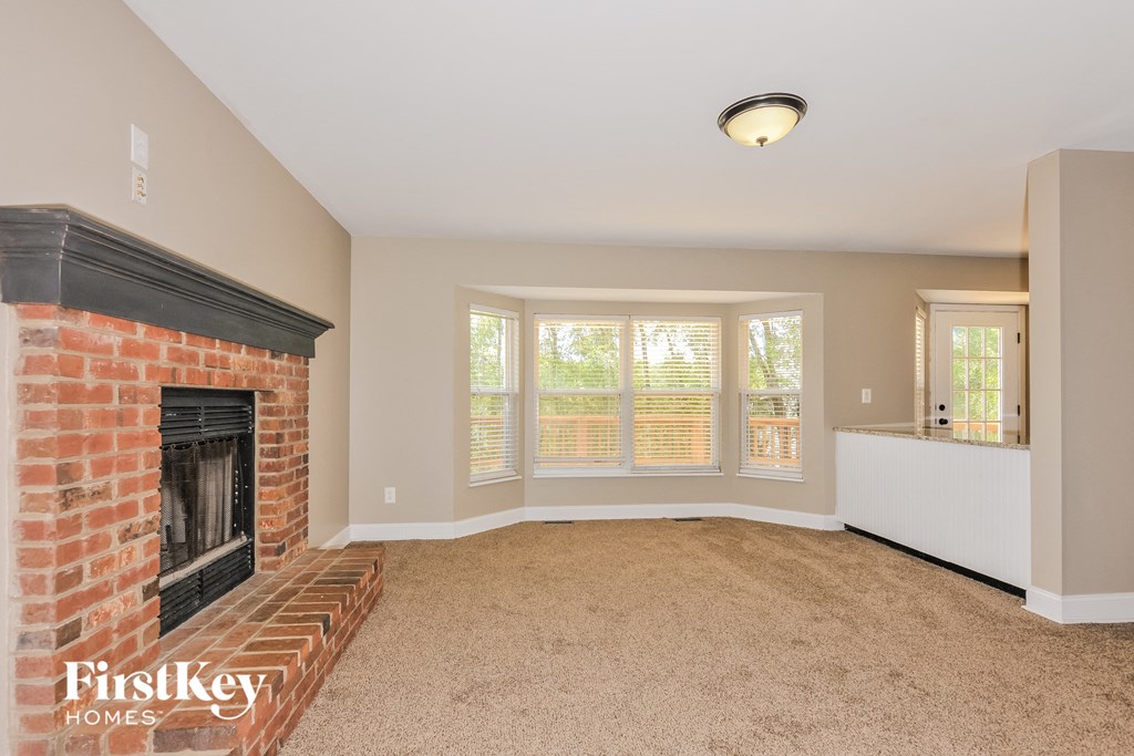 an empty living room with a brick fireplace and a window