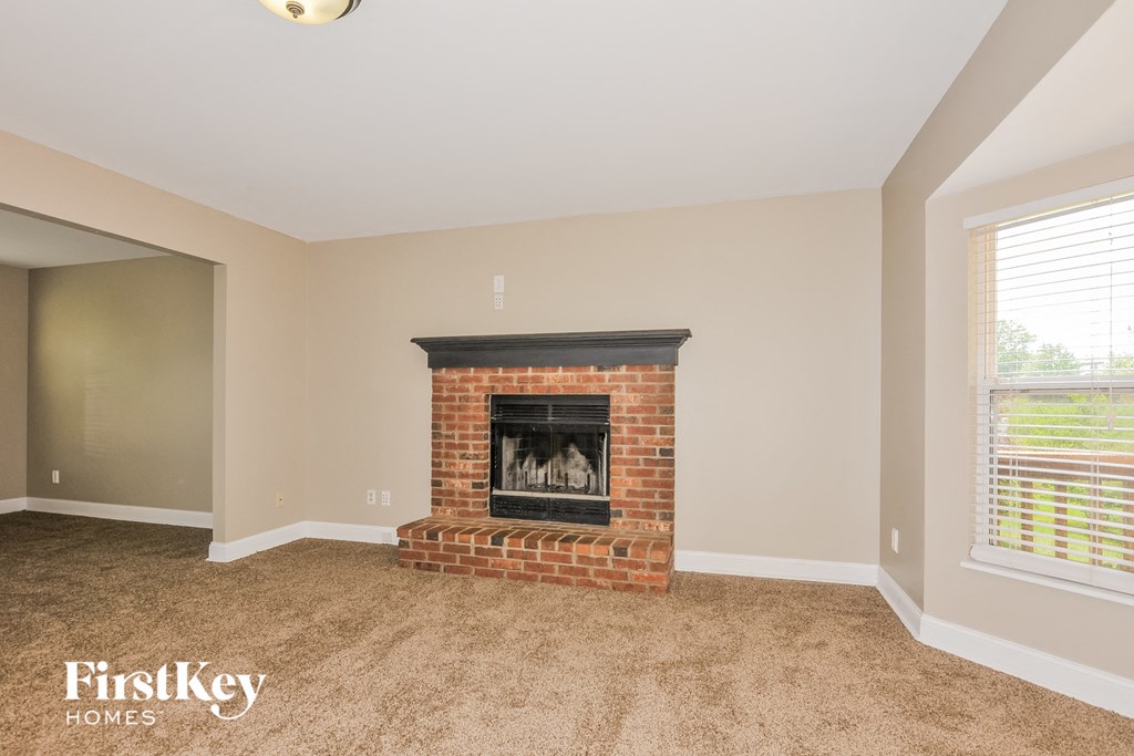 the living room has a brick fireplace and carpeted flooring