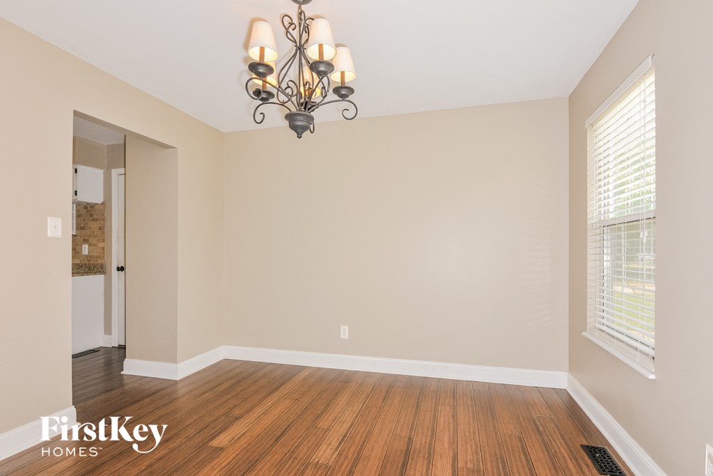 the spacious living room with wood flooring and a chandelier