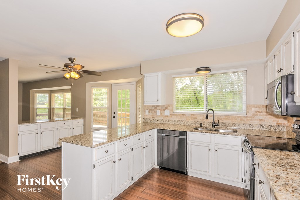 a large kitchen with white cabinets and granite counter tops