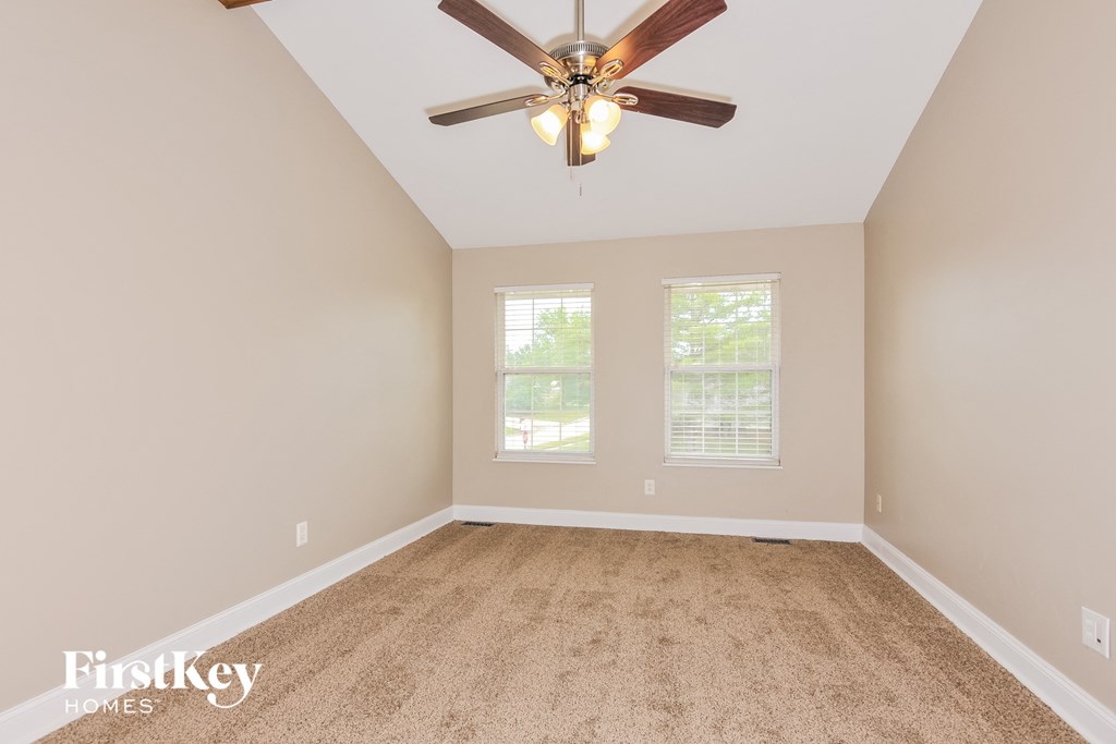 an empty room with a ceiling fan and two windows