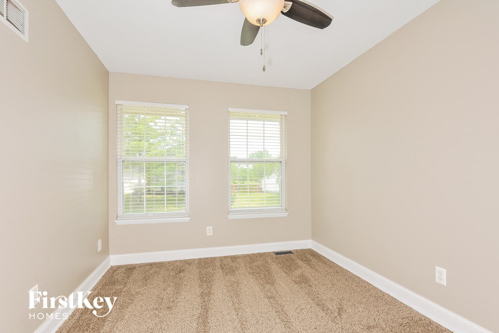a empty room with a ceiling fan and three windows