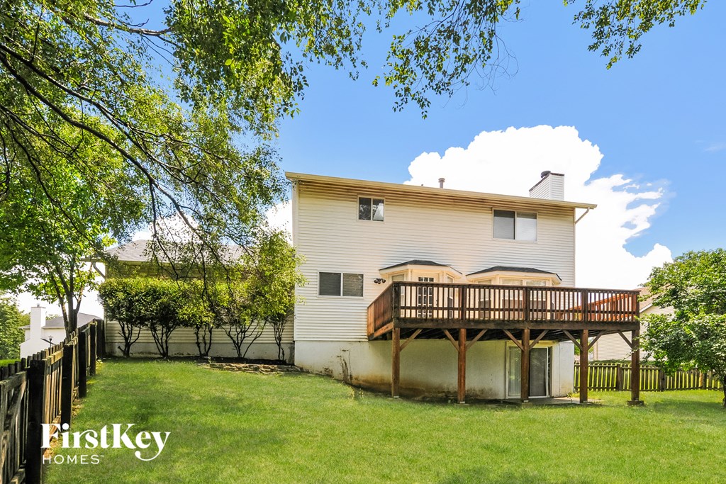 the back of a house with a deck on top of a wooden fence