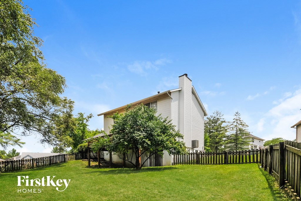 a small white house with a tree next to a fence