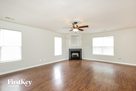 an empty living room with a ceiling fan and a fireplace